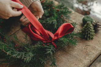 a red bow being tied on the top of a christmas wreath