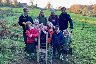 adults and children with tree planted at allestree park