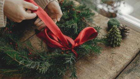 a red bow being tied on the top of a christmas wreath